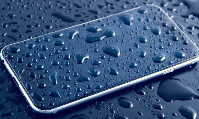 Smartfon pokryty kroplami wody, podkreślający jego wodoodporność IP.