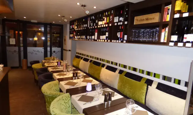 Tables dressées dans un restaurant à Aurillac, idéal pour un repas du dimanche. Les étagères débordent de bouteilles de vin.