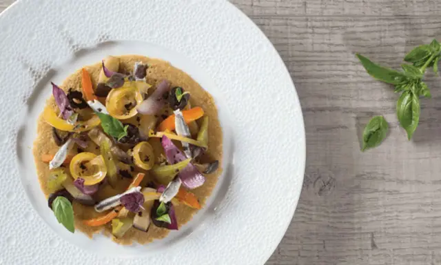 Socca garnie de légumes colorés et d'anchois, une idée pour votre recette socca.