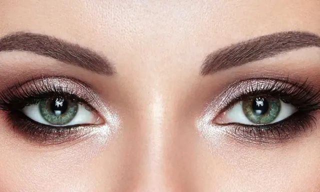 Ojos verdes deslumbrantes con un maquillaje ahumado y brillante, realzando su belleza natural.