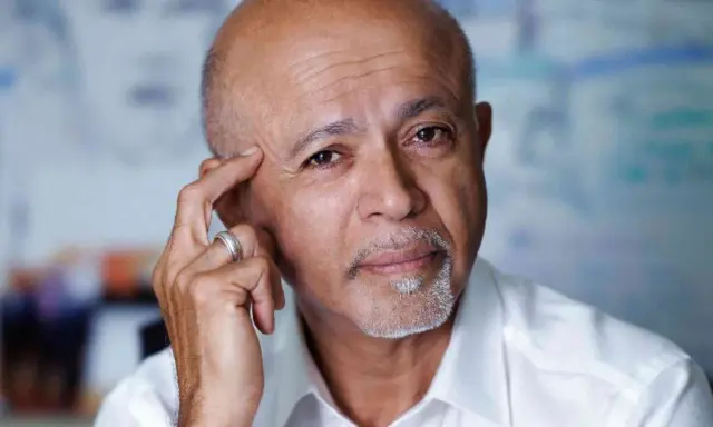 Ritratto di Abraham Verghese, con la mano sulla tempia, pensieroso.