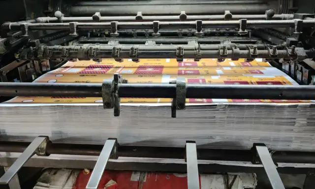 Maszyna drukarska wykorzystująca technikę druku płaskiego drukuje wzory na papierze.