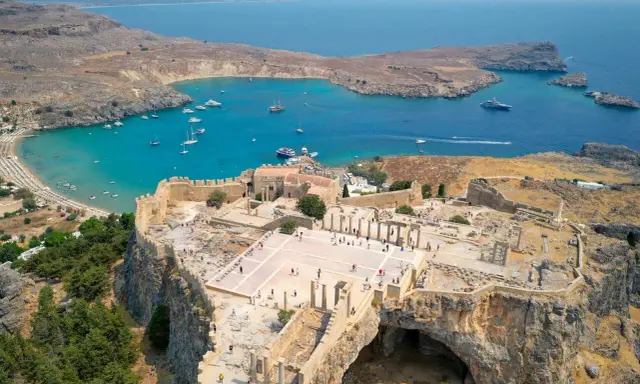 Akropol w Lindos na Rodos, z widokiem na turkusową zatokę i plażę. Wspaniałe ruiny przypominają o dawnej świetności, a nie o koszmarze.