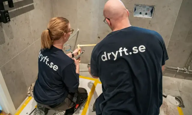 Två hantverkare från dryft.se mäter upp för att byta kommod i ett badrum.