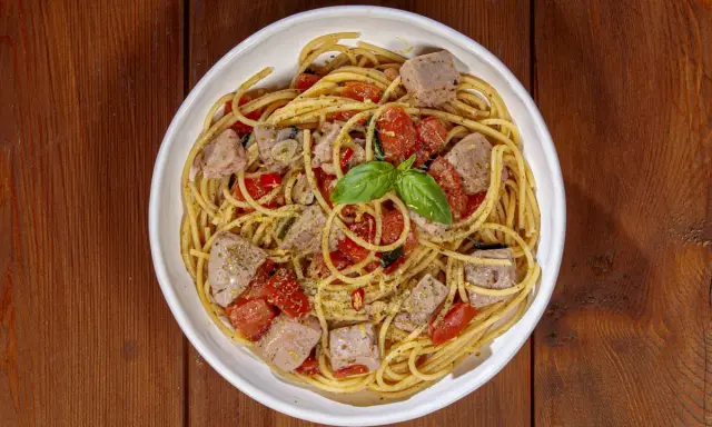 Spaghetti al tonno, un classico profumato, come la spaghetti al tonno ricetta della nonna, con pomodorini e basilico fresco.