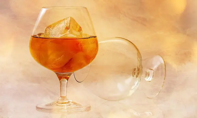 Kieliszek z brandy i lodem, obok pusty, przewrócony kieliszek. Idealny sposób, jak pić brandy.