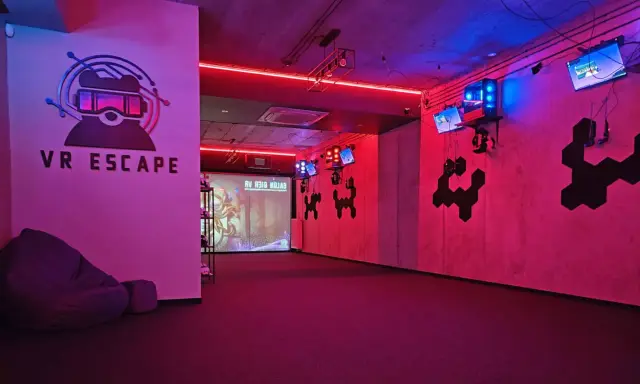 Częstochowa escape room z neonowym oświetleniem, logo VR ESCAPE i ekranem projekcyjnym.
