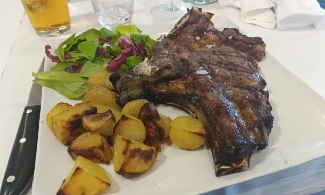 Costata di manzo succulenta con patate arrosto e insalata fresca, un piatto da re.