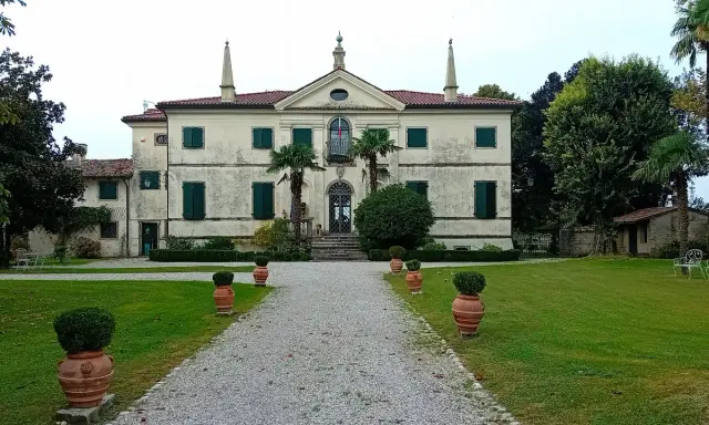 Villa storica con viale di ghiaia e vasi decorativi. Un luogo incantevole per scoprire cosa vedere a Clauiano.
