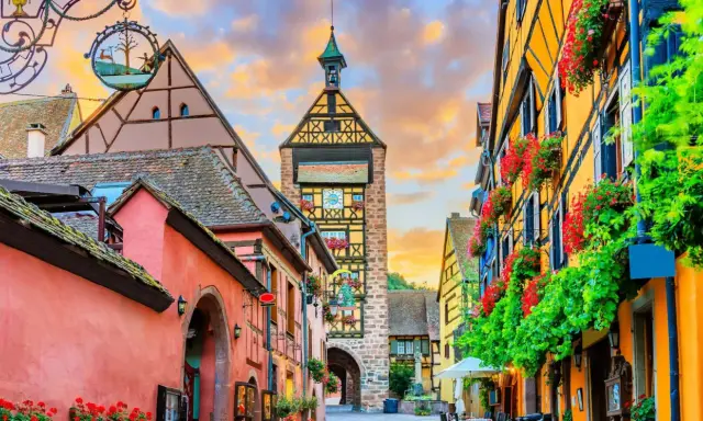 Un pueblo de cuento en Alsacia, con casas coloridas, flores y una torre con reloj. ¡Mucho que ver en Alsacia!