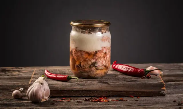 Słoik z mięsem, czosnek i papryczki chili. Przygotowanie tyndalizacji mięsa w piekarniku.