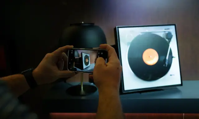 Ręce trzymają smartfon, fotografując gramofon. Odkryj gadżety do domu, o których nie miałeś pojęcia, jak ten nowoczesny sposób na docenienie klasycznej muzyki.