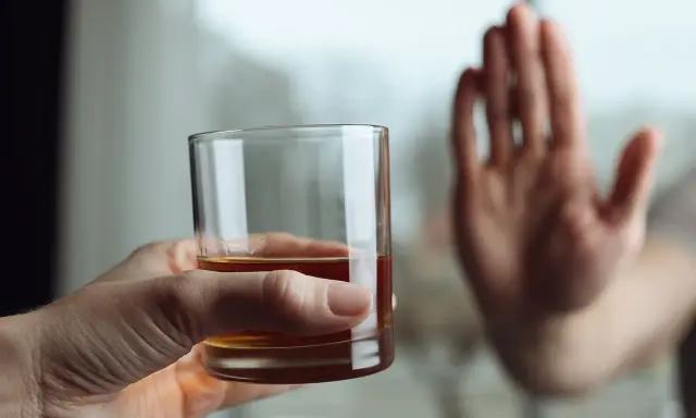 Dłoń odrzuca szklankę z alkoholem, symbolizując decyzję o zerwaniu z nałogiem. To koniec drogi, która mogła prowadzić do zgonu po esperalu.