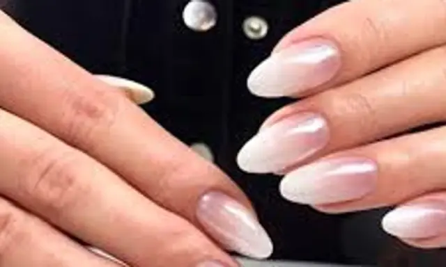 Dłonie z paznokciami w stylu french z pyłkiem, delikatny ombre od różu do bieli, subtelny blask.