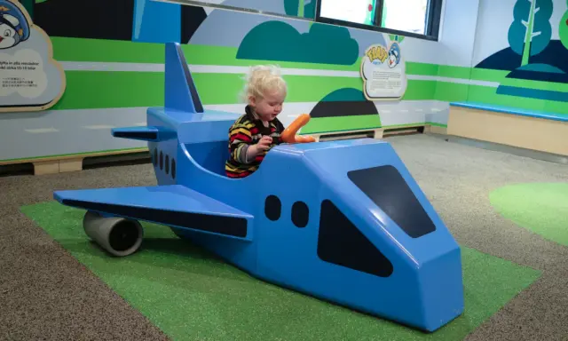 Liten pojke leker i ett blått leksaksplan. En rolig resa med bebis börjar här!