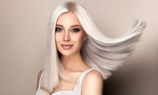 Kobieta z olśniewającymi, długimi włosami w odcieniu perłowy blond, które falują na wietrze.