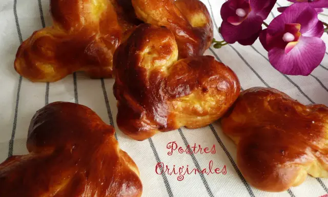 Pan de leche dorado y esponjoso, con forma de corazón, junto a orquídeas moradas. ¡Postres originales para disfrutar!