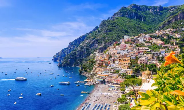 Färgstarka hus klättrar uppför bergssluttningen vid en livlig strand. Perfekt för din resa till Italien tips!