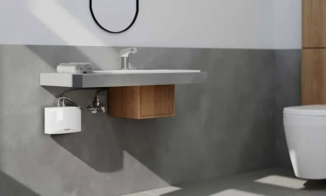 Moderner **Durchlauferhitzer** unter dem Waschbecken im **Bad**. Neben dem WC und dem Waschbecken mit Holzelement.