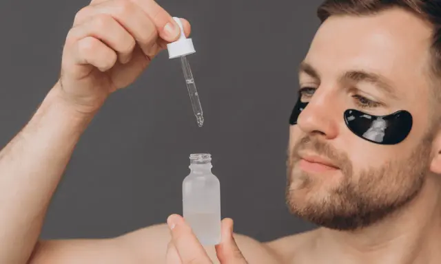 Homme appliquant un sérum, se demandant acide glycolique combien de fois par semaine. Patchs noirs sous les yeux pour un soin ciblé.