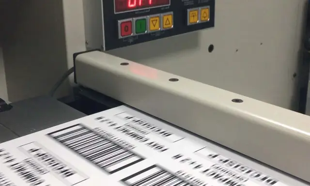 Máquina de impresión offset digital procesando etiquetas con códigos de barras.