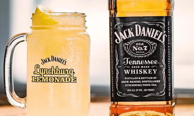 En iskallad Jack Daniel's Lynchburg Lemonade i ett glas med handtag, bredvid en flaska Jack Daniel's Tennessee Whiskey.