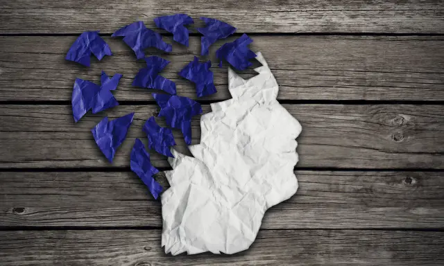 Zgnieciona papierowa głowa, której fragmenty odlatują, symbolizuje problem z pamięcią krótkotrwałą.