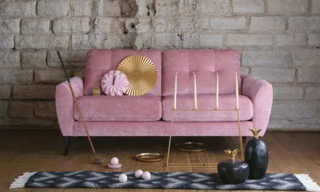 En dyr soffa i sammet, rosa, med dekorativa föremål som en golfklubba, bollar, ljusstakar och ananasskulpturer.