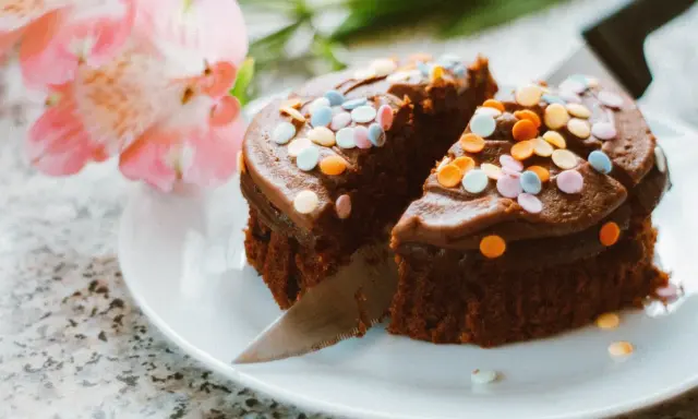 Schokoladenkuchen mit bunten Streuseln, angeschnitten. Eine kreative Idee, um Kuchenreste verwerten und nochmals genießen zu können.