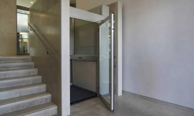 Una piattaforma elevatrice accanto a una scala, una soluzione per chi cerca come abbassare i gradini di una scala, rendendo l'accesso più agevole.