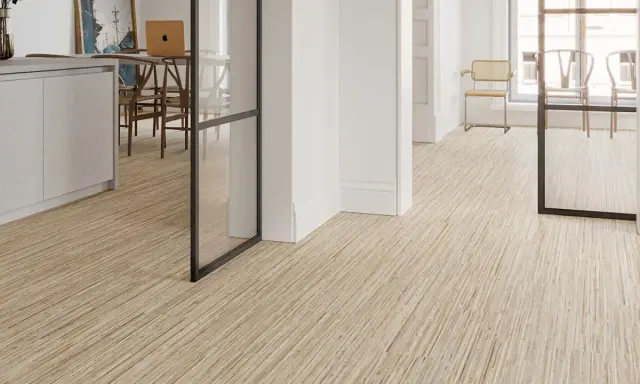 Un moderno revestimiento del suelo de madera clara con un diseño lineal crea un ambiente acogedor en un interior luminoso.