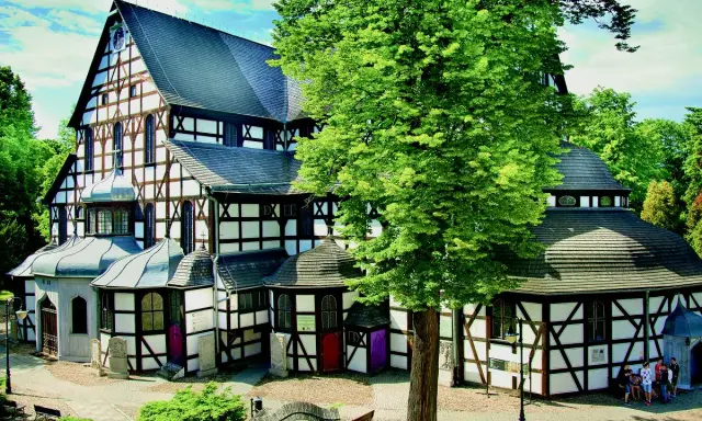 Kościół Pokoju w Świdnicy, z charakterystyczną szachulcową architekturą, otoczony zielenią.