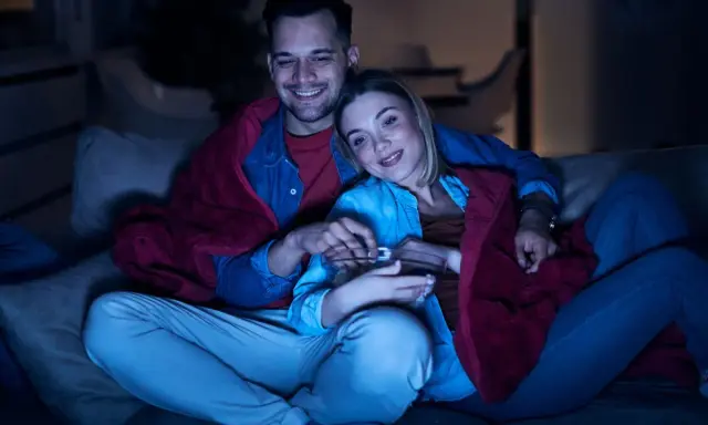 Para spędza miły wieczór, otulona kocem, oglądając lekkie filmy na wieczór i jedząc popcorn.