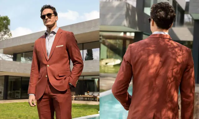 Man in a rust-colored suit, embodying a festive dress code for males, poses outdoors by a modern house and pool.