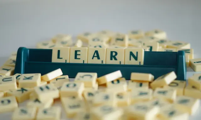 Litery na kafelkach układają się w słowo LEARN, symbolizując naukę i rozwijanie słownictwa. To świetny przykład na word formation C1.