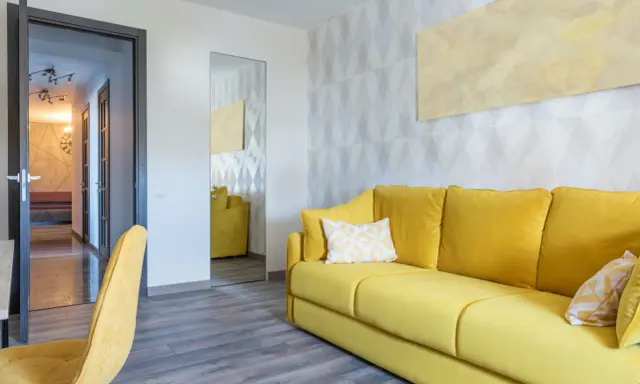 Un sofá amarillo vibrante y un sillón a juego llenan la habitación, destacando los alegres colores de sofás.