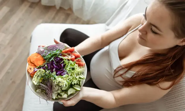 Kobieta w ciąży delektuje się zdrową sałatką, dbając o dietę w ciąży. Kolorowe warzywa to podstawa.