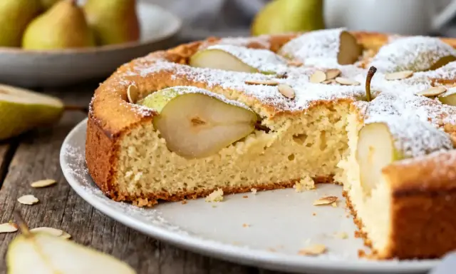Gâteau poire moelleux, saupoudré de sucre glace et garni de fines lamelles d'amandes. Des poires fraîches sont intégrées dans la pâte.