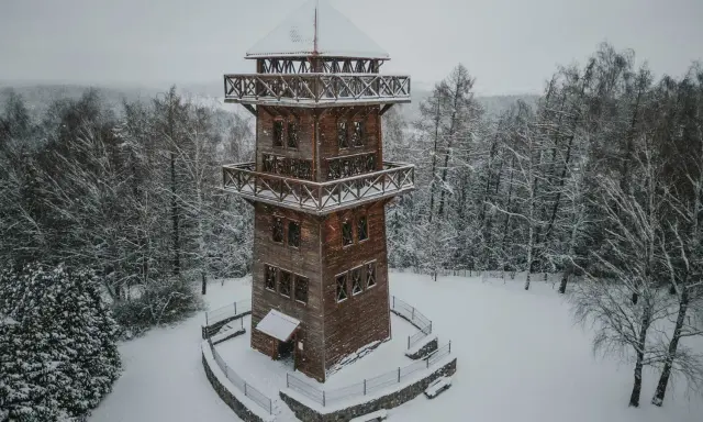 Drewniana wieża widokowa na Mazurach w zimowej scenerii. Otoczona ośnieżonym lasem, zaprasza do podziwiania krajobrazu.