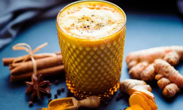 Ein Glas goldene Milch mit Kurkuma, Ingwer, Zimt und Sternanis. So wird goldene Milch gemacht.