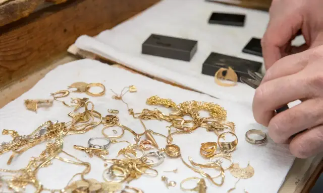 Mani esperte valutano gioielli d'oro, anelli e collane, un modo pratico per imparare come riconoscere l'oro.