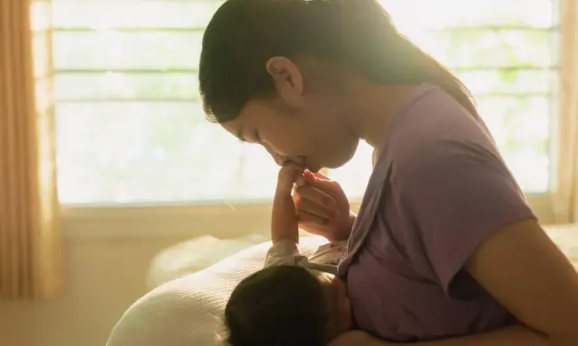 Dolce momento tra madre e neonato. La mamma bacia la manina del piccolo, attenta ai suoi segnali fame.