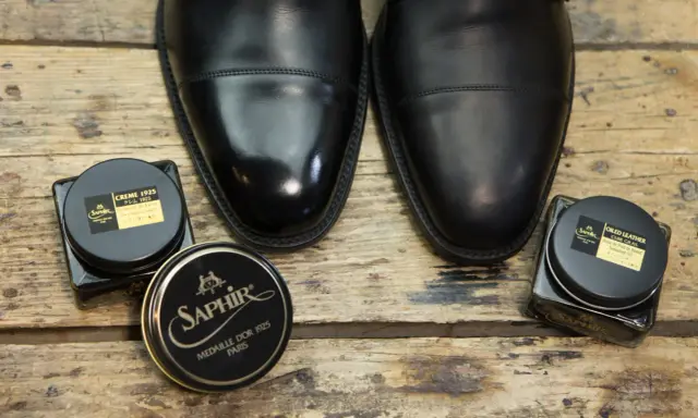 Czarne, eleganckie buty i dwa słoiczki Saphir: krem do skóry i olejek. Idealne, by dowiedzieć się, czym natłuścić skórzane buty.