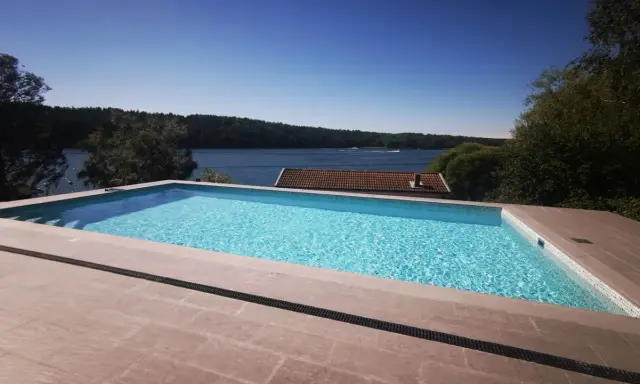 En lyxig pool med klarblått vatten och en fantastisk utsikt över en sjö. En dröm för många, men vad är bygga pool kostnad?