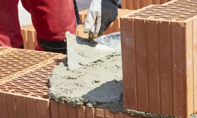 Budowanie muru z pustaków ceramicznych, nakładanie zaprawy. Właśnie tak jak zrobic cement do budowy.