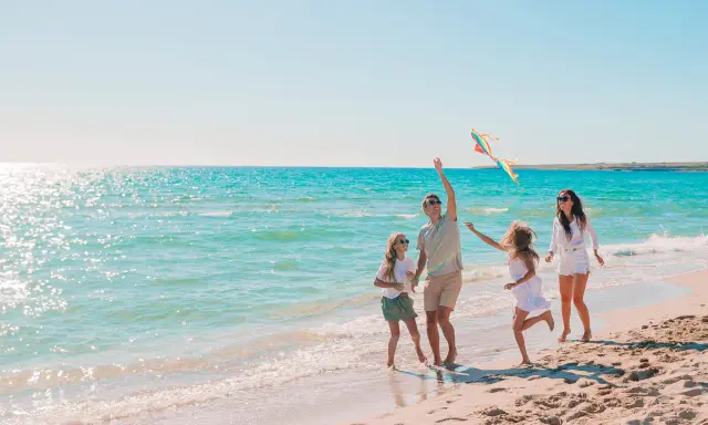 Rodzina puszcza latawiec na piaszczystej plaży. Piękne kąpieliska nad Bałtykiem zachęcają do zabawy.