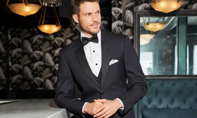 A man in a sharp tuxedo, perfect for any black tie event or formal occasion. He embodies the classic tuxedo dress code with a crisp white shirt and bow tie.