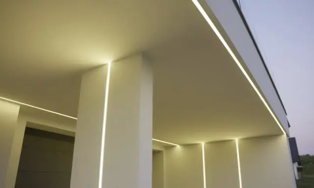 Nowoczesny budynek z subtelnym oświetleniem. Wbudowany profil LED w ścianie tworzy eleganckie linie światła, podkreślając architekturę.