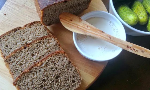Kromki pysznego chleba z mąki razowej, obok miseczka z mlekiem i ogórki kiszone. Idealny zestaw na śniadanie.