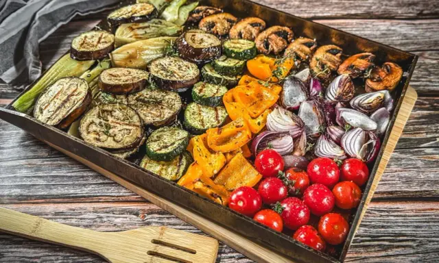 Buntes Gemüse wie Auberginen, Zucchini, Paprika, Zwiebeln und Tomaten auf einem Blech für ein köstliches vegetarisches Grillen.